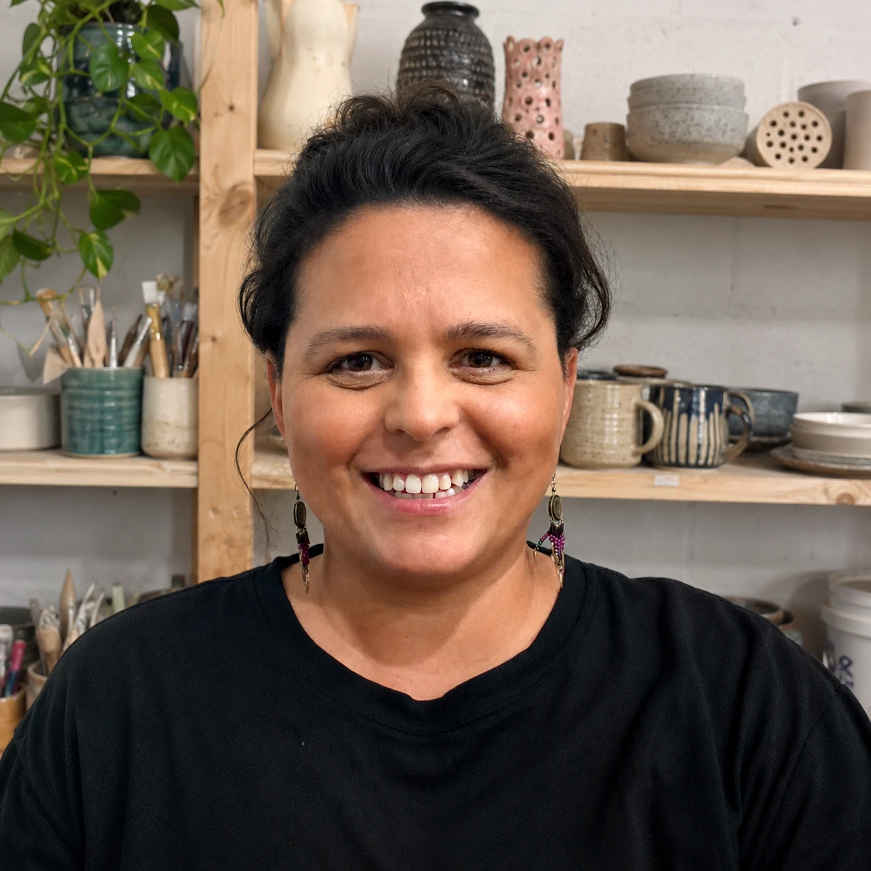 Alicia Rodriguez smiling in front of shelves of pottery and art tools