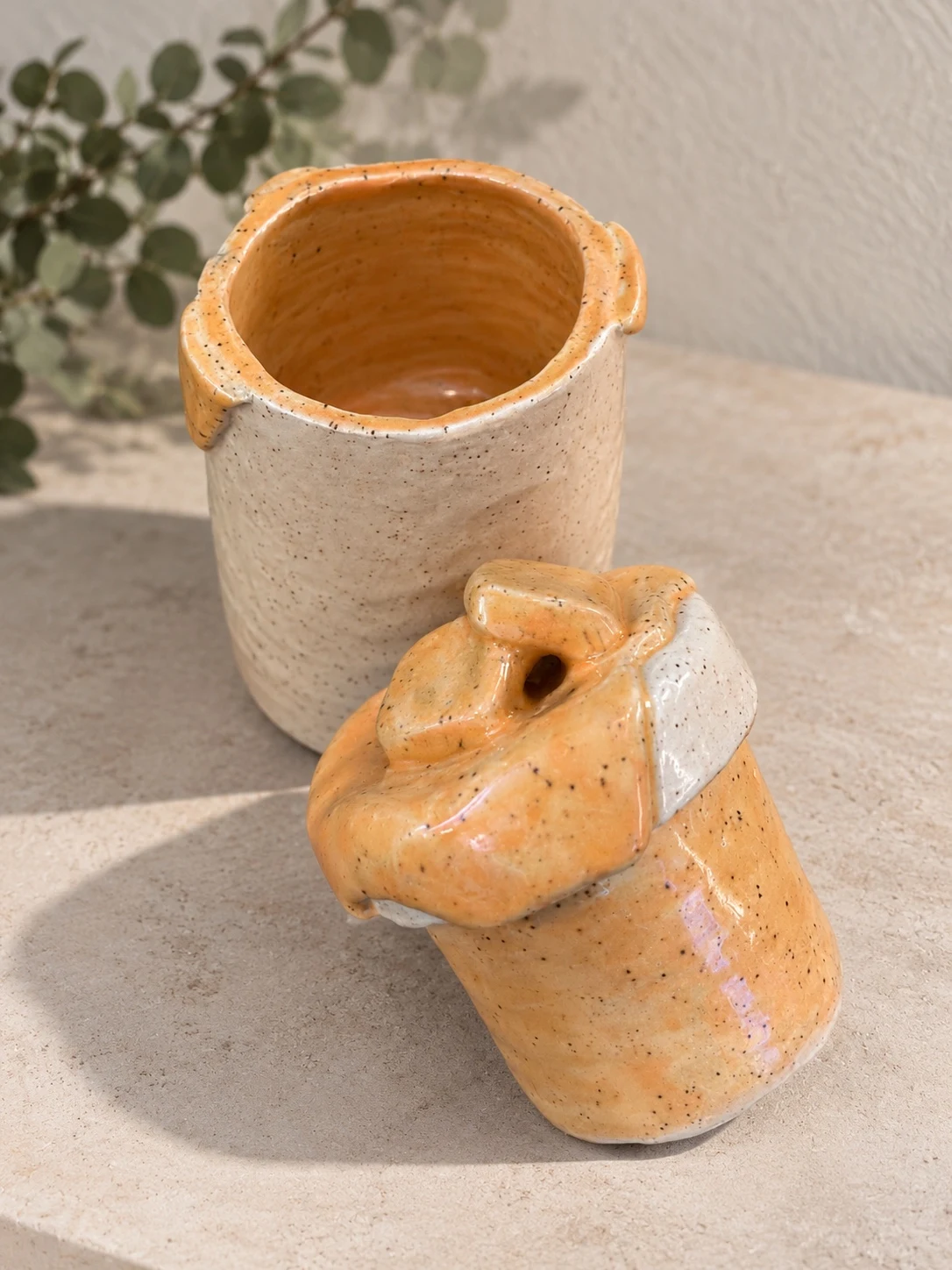 Open cream and orange ceramic jar with its matching lid and inner piece displayed alongside