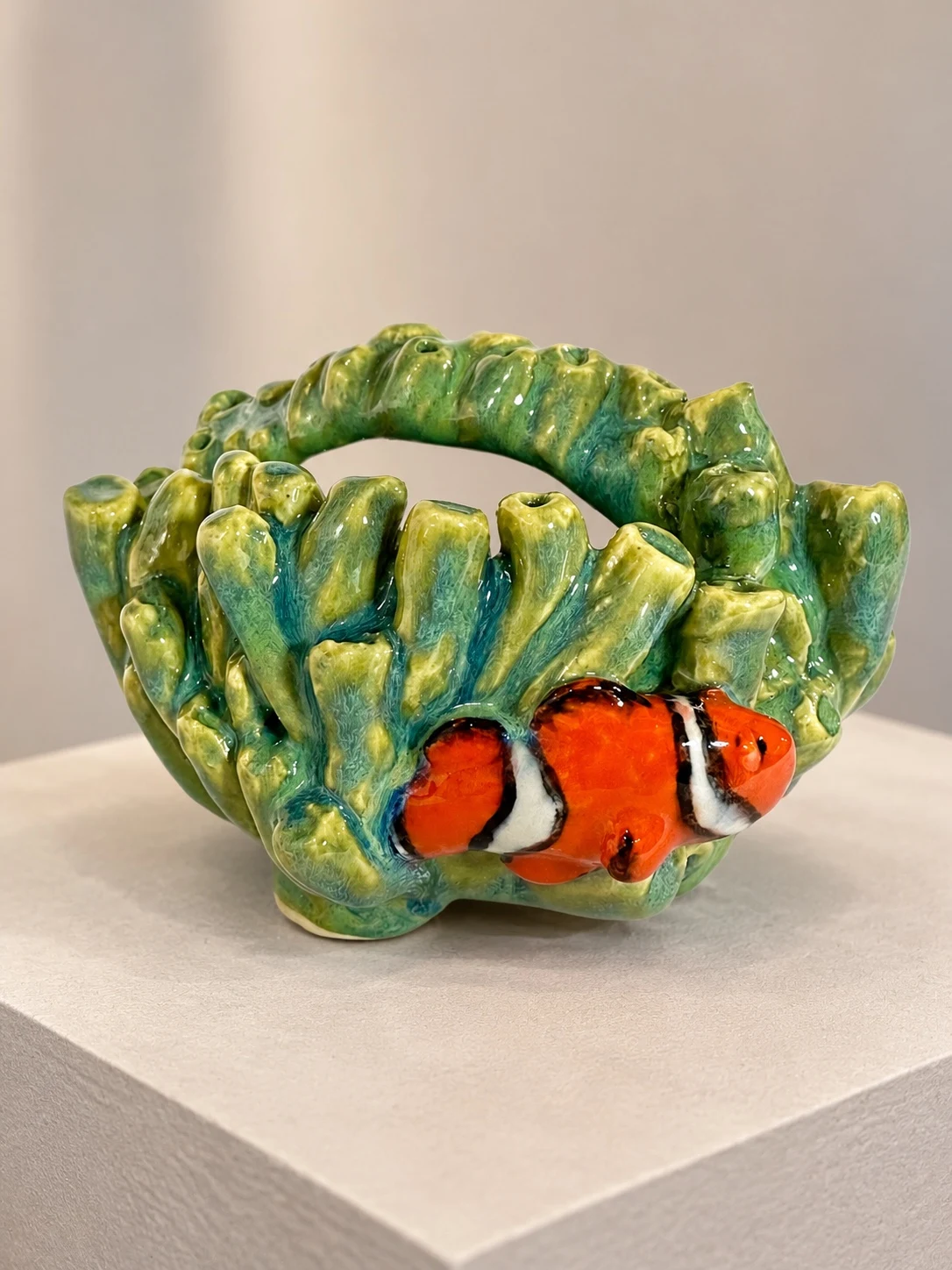 Orange clownfish nestled against sculpted green and turquoise coral