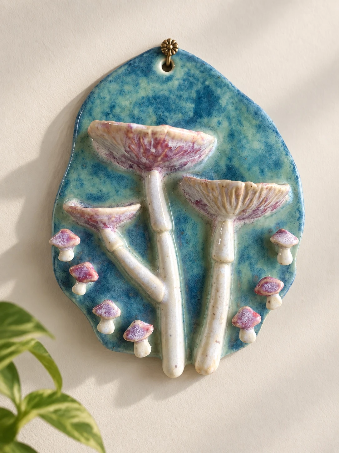 Blue ceramic wall hanging with raised cream and pink mushrooms